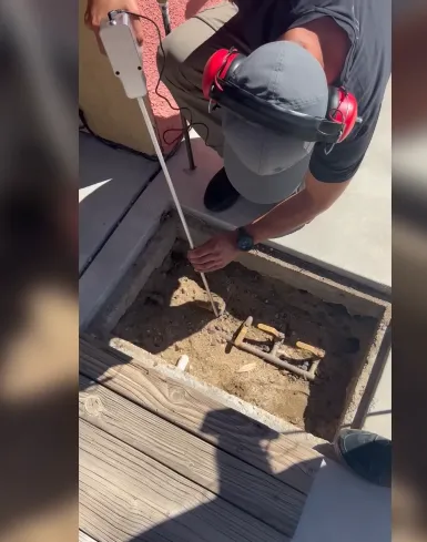 Technician listening for a leak at a buried valve box