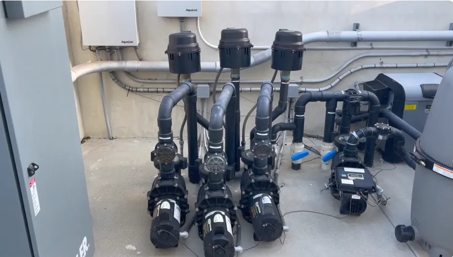 Pool equipment pad with pumps and valves being checked for leaks