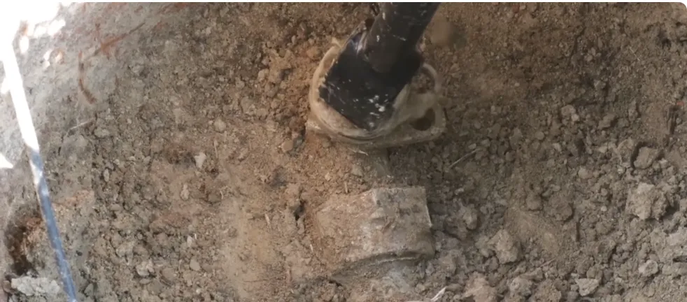 Small excavation exposing a buried water line in a yard